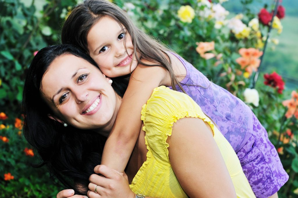 beautiful mom and daughter outdoor in garden together with flower have fun and hug